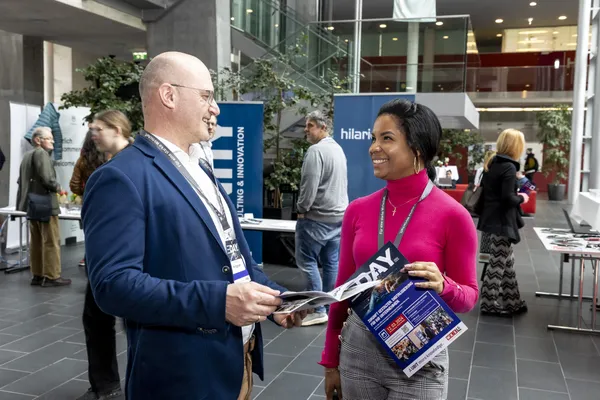 2024: Zwei Personen im Foyer im Gespräch und mit Broschüren beim eDay Salzburg.