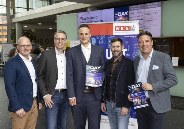 2024: Gruppe posiert mit eDay-Prospekten vor Informationsstand beim eDay Salzburg.