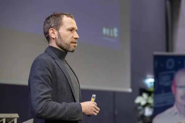 2024: Vortragende Person im Profil hält Präsentationsfernbedienung auf der Bühne beim eDay Salzburg.