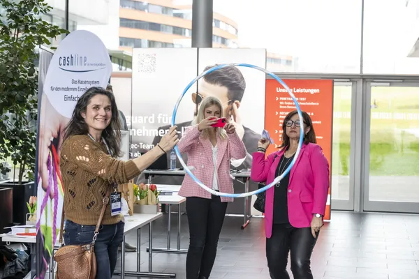 2024: Personen posieren mit einem blauen Ring als Aktions-Requisit am Stand beim eDay Salzburg.