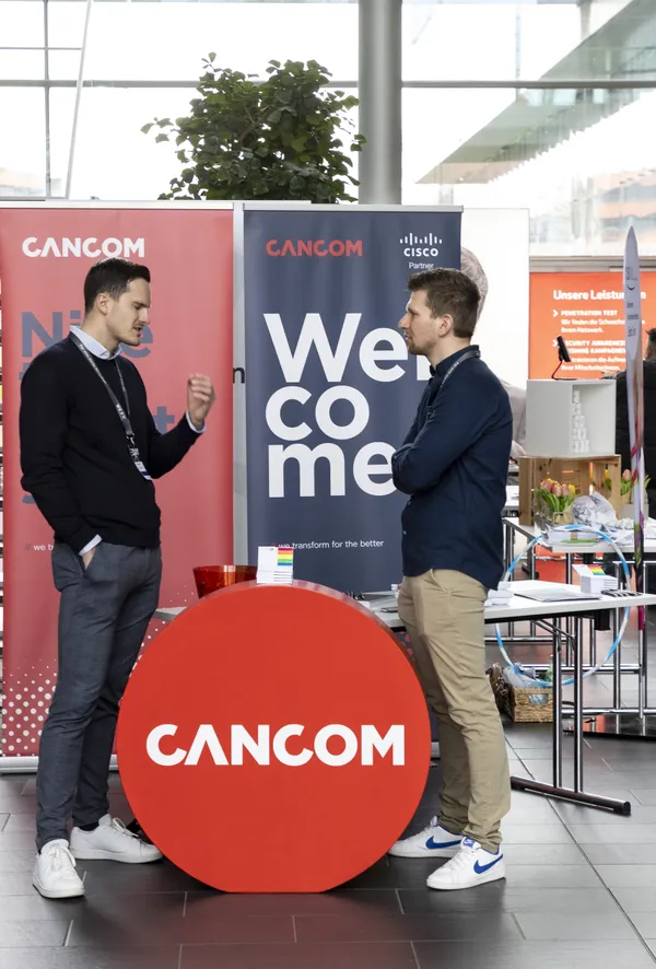 2024: Zwei Personen unter einem 'Welcome'-Banner im Gespräch am Ausstellerstand beim eDay Salzburg.
