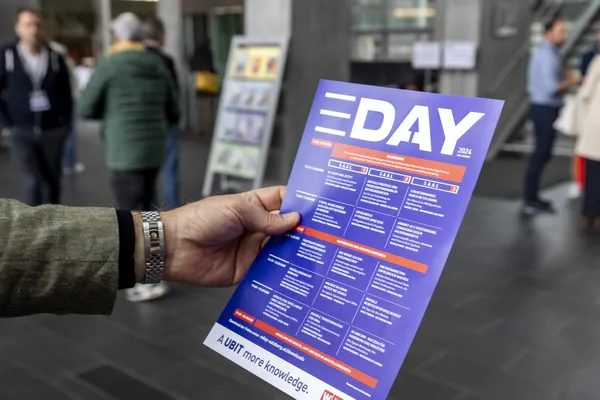 2024: Hand hält das Programmflyer des eDay im Foyer beim eDay Salzburg.