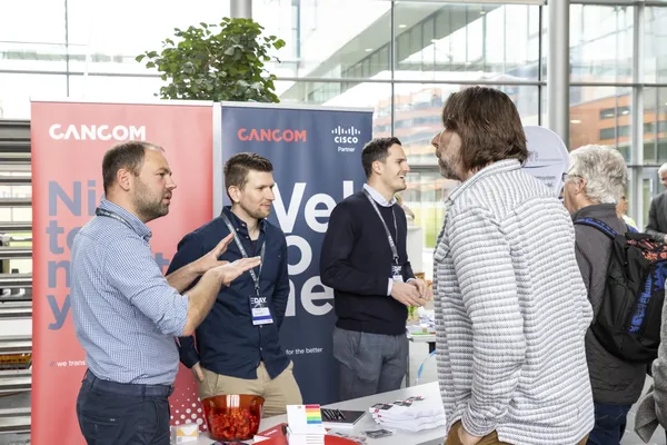 2024: Mehrere Personen im Gespräch an einem CANCOM-Ausstellerstand.