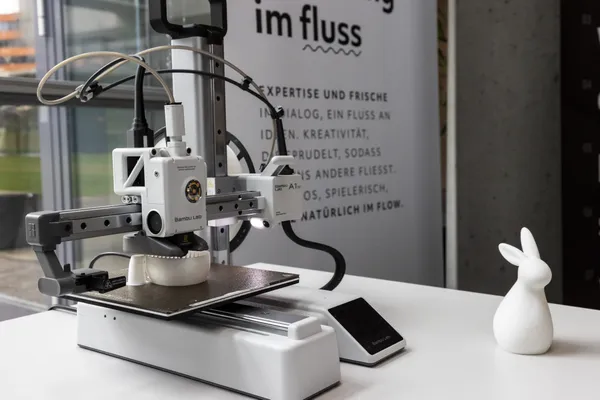 2024: Nahaufnahme eines 3D-Druckers mit gedrucktem Objekt auf einem Tisch.