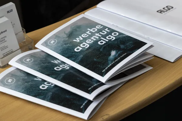 2024: Broschüren mit dem Titel 'werbe agentur algo' auf einem Tisch.