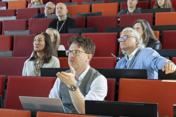 2025: Teilnehmender meldet sich mit Handgeste und Blick Richtung Bühne beim eDay Salzburg.