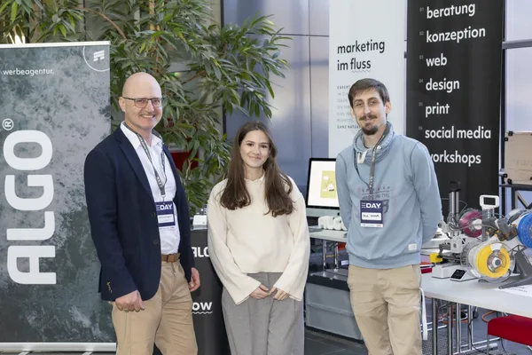 2025: Drei Personen vor Ausstellerstand mit 'ALGO'-Logo und Präsentation beim eDay Salzburg.