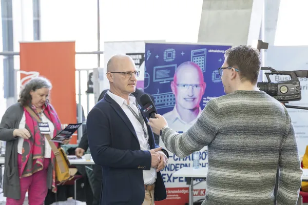 Mann wird am Stand interviewt, Mikrofon und Kamera sind sichtbar beim eDay Salzburg 2025