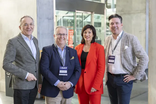 Vier Personen mit E‑DAY-Badges posieren im Foyer beim eDay Salzburg 2025