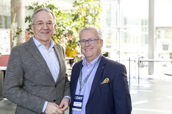 Zwei Teilnehmende mit E‑DAY-Badge im hellen Foyer beim eDay Salzburg 2025