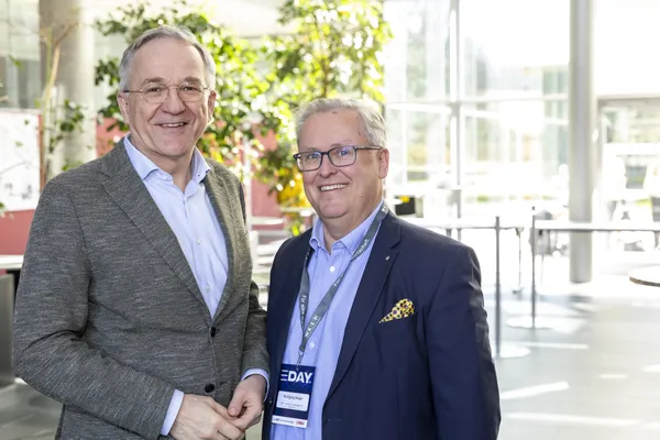 Zwei Teilnehmende mit E‑DAY-Badge im hellen Foyer beim eDay Salzburg 2025