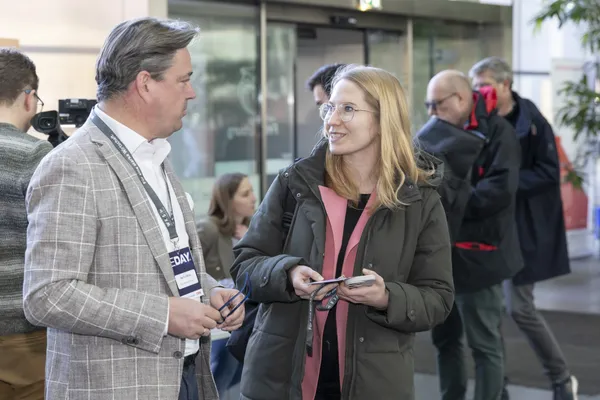 Zwei Personen im Gespräch im Foyer, andere Teilnehmer im Hintergrund beim eDay Salzburg 2025