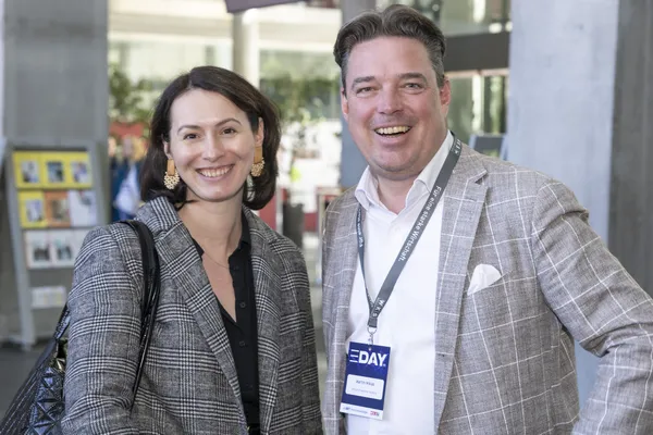 Zwei Personen lächeln in der Konferenzlobby, einer mit E‑DAY-Badge, beim eDay Salzburg 2025