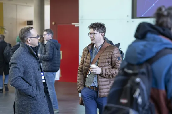 Zwei Männer im Gespräch im Foyer, einer hält einen Kaffee, beim eDay Salzburg 2025