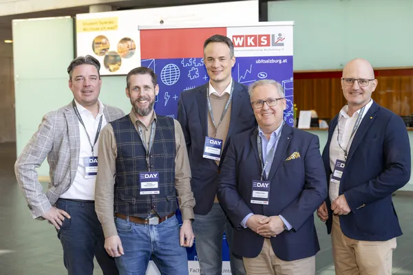 Fünf Personen posieren vor einem WKS-Banner mit E‑DAY-Badges beim eDay Salzburg 2025
