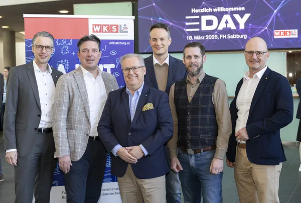 Sechs Personen stehen vor Banner und Bildschirm mit eDay Salzburg 2025 im Eingangsbereich.