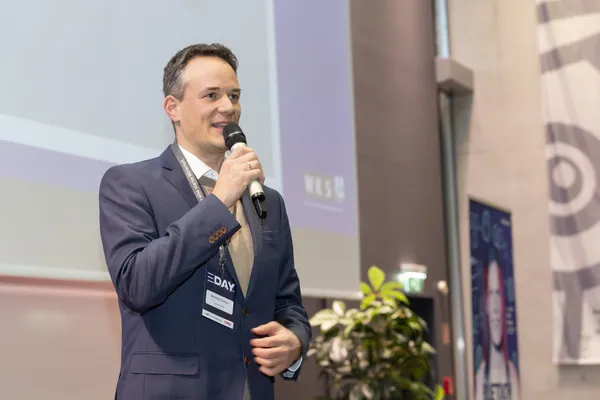 Vortragender mit Mikrofon auf der Bühne beim eDay Salzburg 2025.