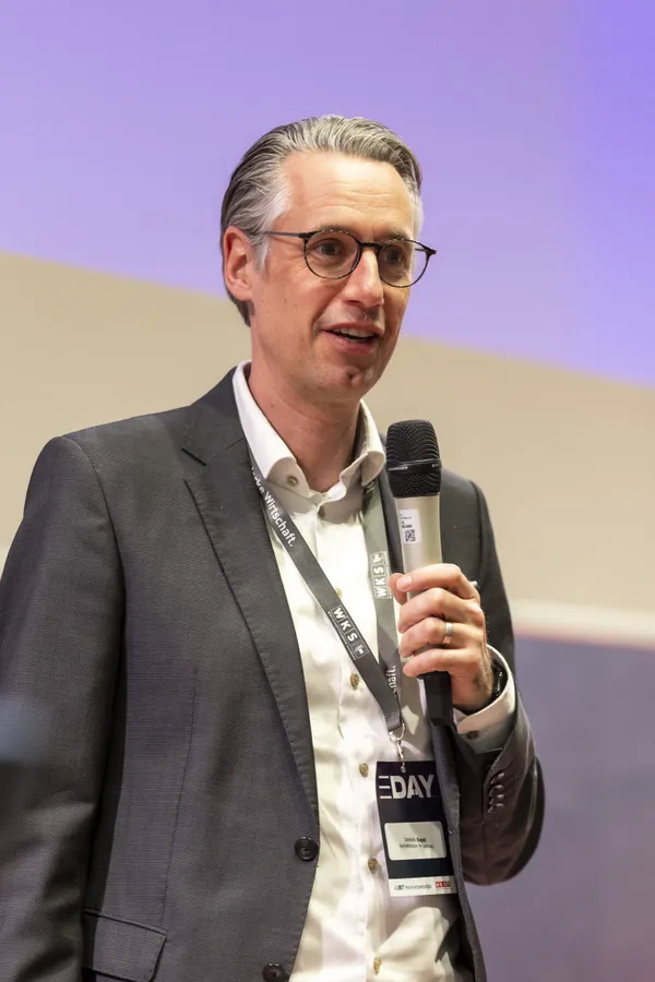 Vortragender mit Mikrofon und Badge auf der Bühne beim eDay Salzburg 2026.