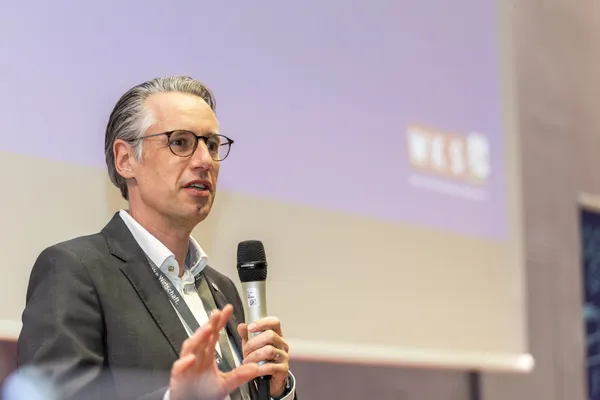 Vortragender gestikuliert mit Mikrofon auf der Bühne beim eDay Salzburg 2026.