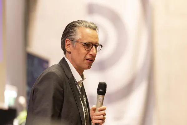 Seitliches Porträt eines Vortragenden mit Mikrofon auf der Bühne beim eDay Salzburg 2026.