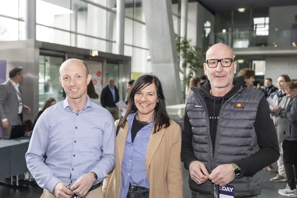 Drei Personen im Foyer des eDay Salzburg 2026, lächelnd.
