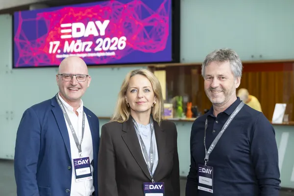 Drei Personen mit Namensschildern vor E‑DAY-Banner '17. März 2026' beim eDay Salzburg 2026.