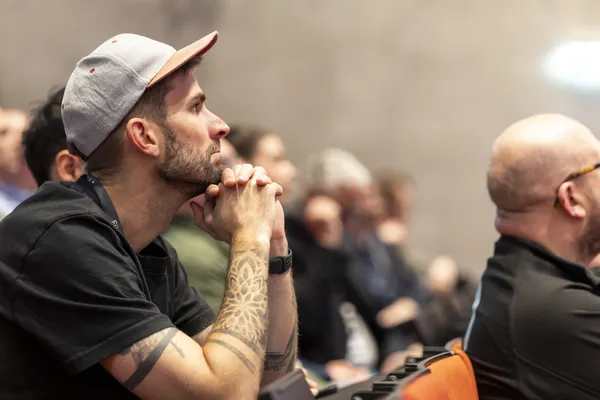 Seitliches Porträt einer Person mit Cap und Tätowierung, aufmerksam im Publikum beim eDay Salzburg 2026.