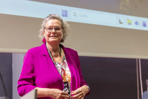 Referentin in pinker Jacke steht vor Leinwand mit Präsentation beim eDay Salzburg 2026.