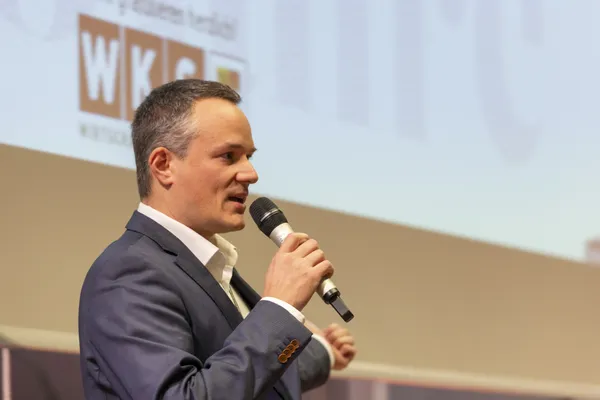 2026: Vortragender mit Mikrofon spricht auf der Bühne vor Leinwand beim eDay Salzburg.