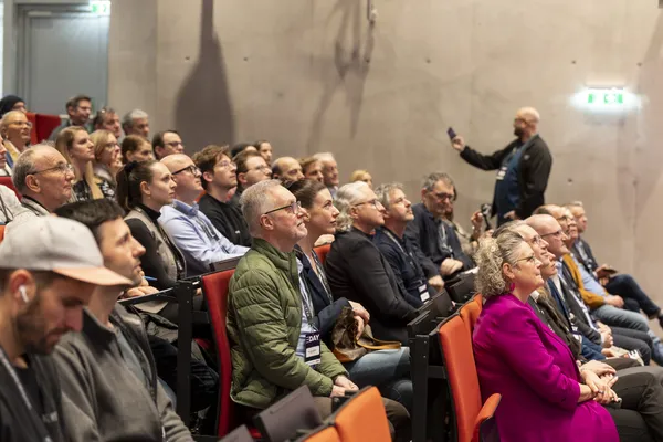 2026: Volles Auditorium mit zuschauenden Gästen, im Hintergrund macht jemand ein Foto beim eDay Salzburg.