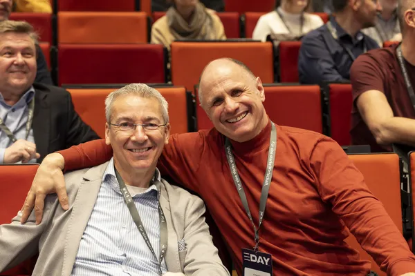 2026: Zwei Personen sitzen nebeneinander und lächeln im Publikum beim eDay Salzburg.